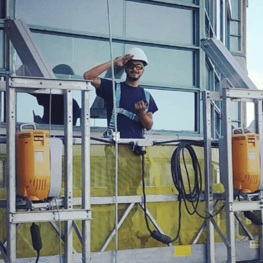 Hakim standing on a building lift looking at camera